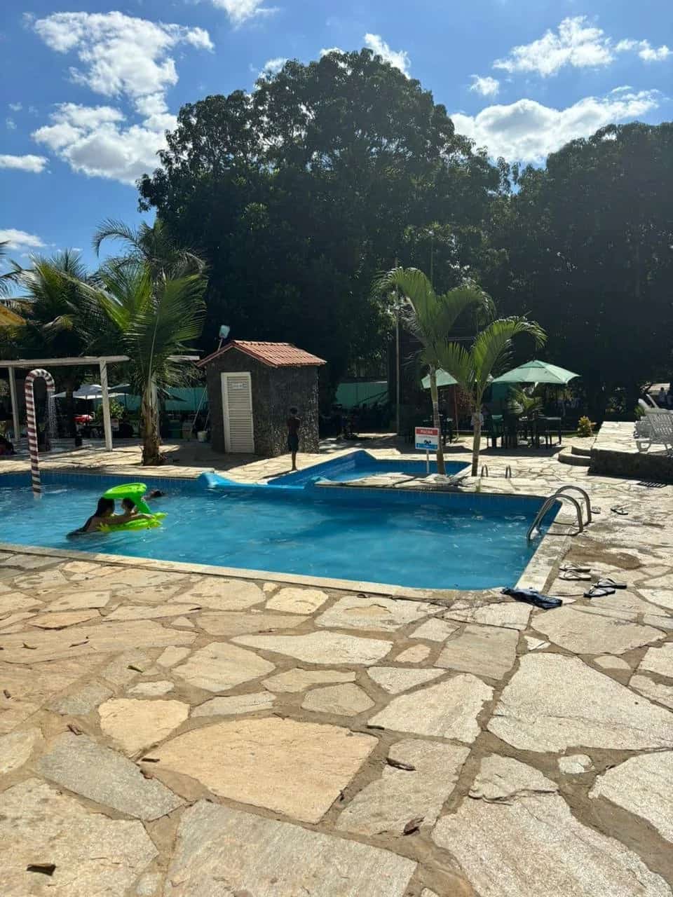 Crianças brincando com boia inflável na piscina em dia ensolarado