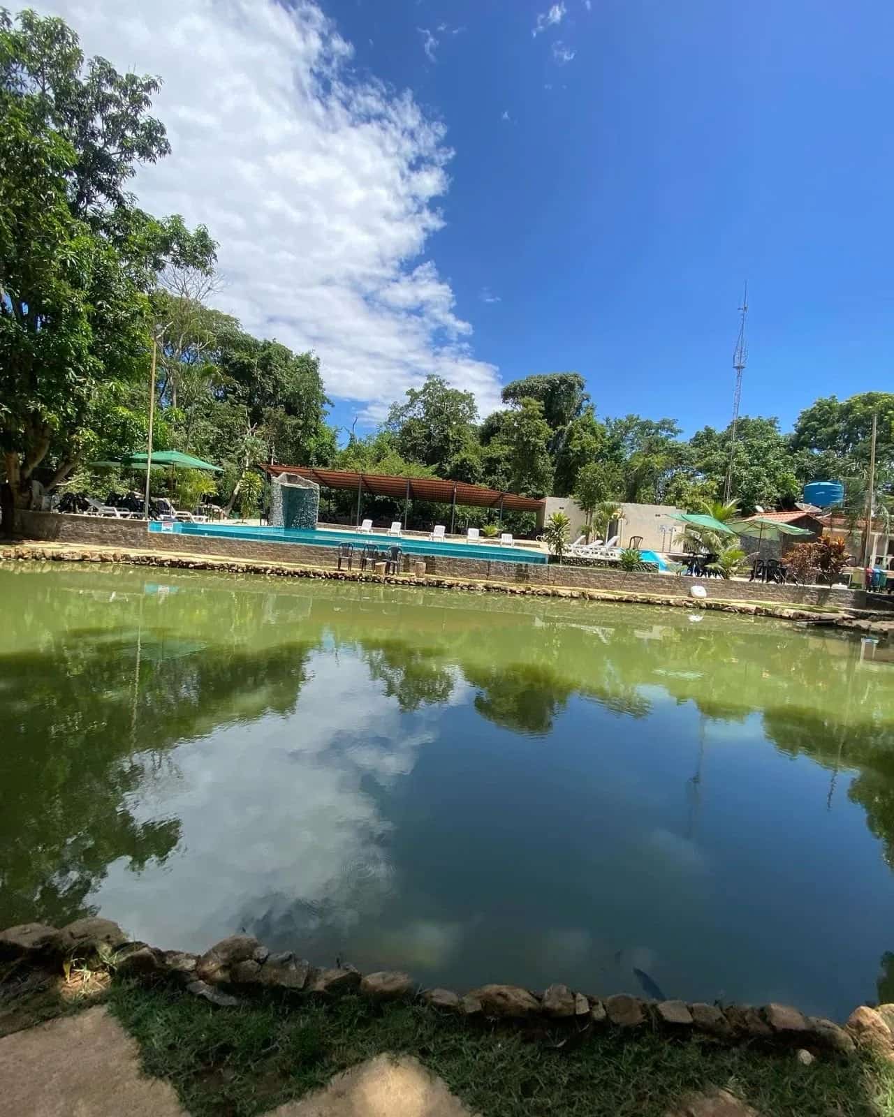 Lagoa ampla refletindo nuvens, com a área de piscinas ao fundo
