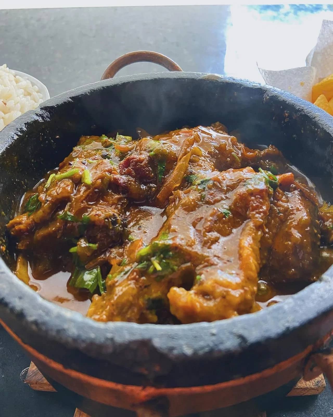 Ensopado de peixe fumegante servido em panela de pedra com arroz