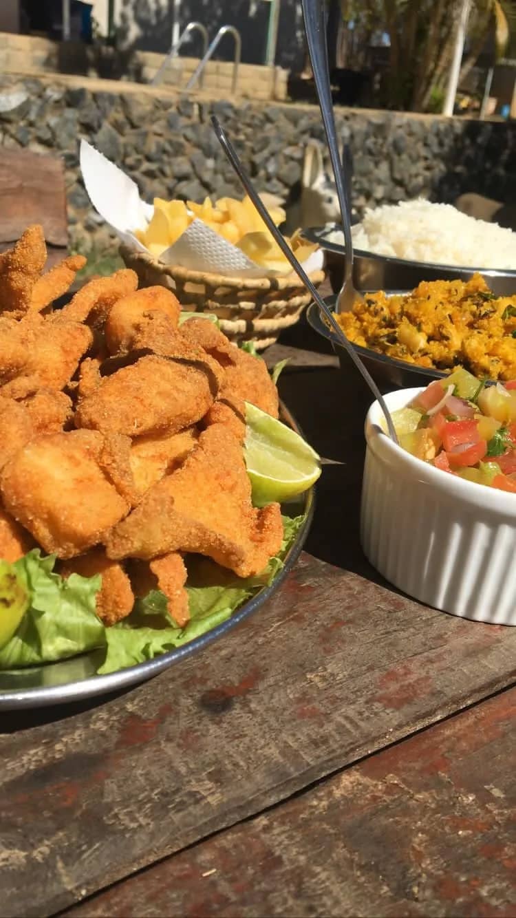 Porção de iscas de peixe empanadas com limão, farofa e vinagrete