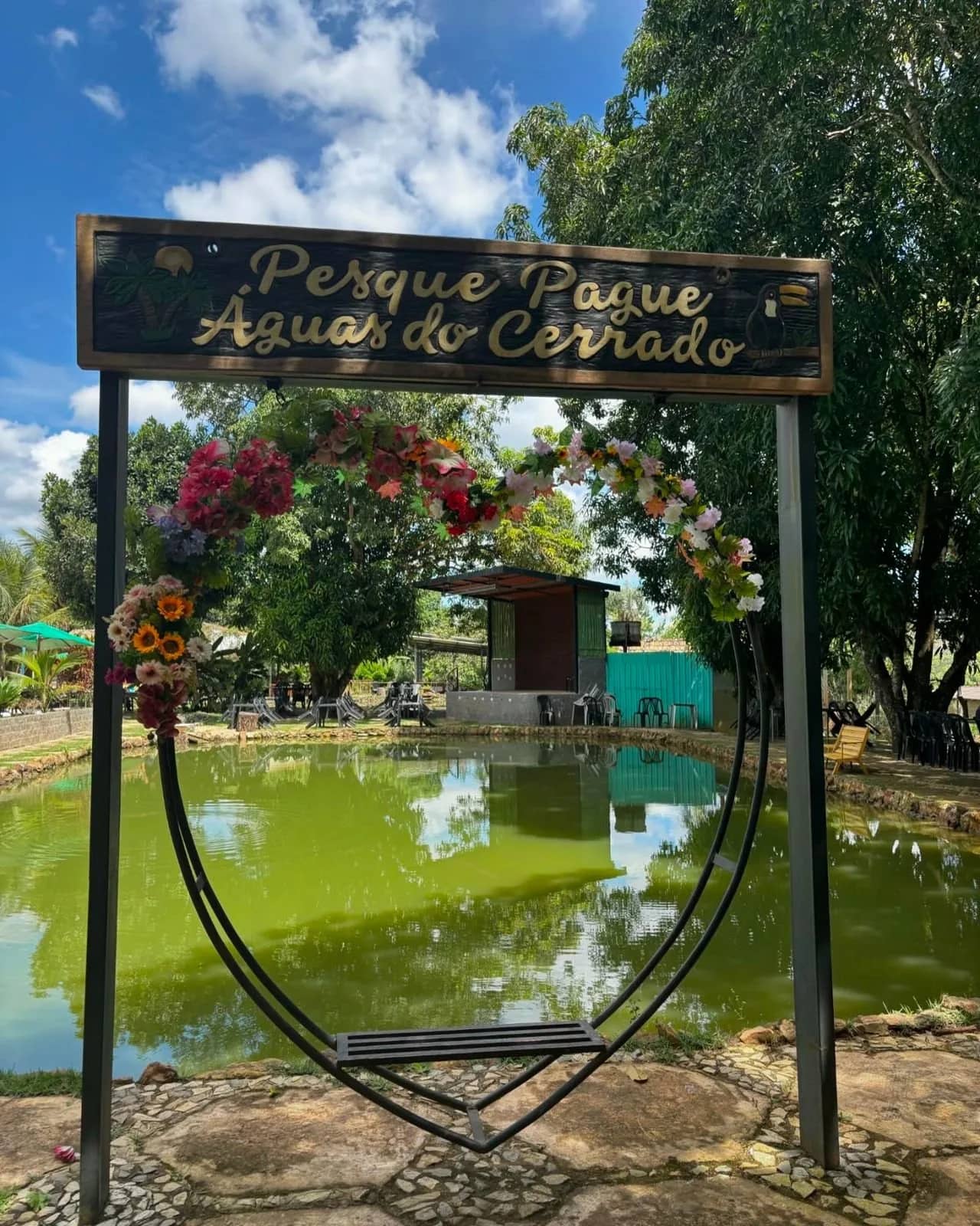 Placa de madeira entalhada na entrada com balanço florido diante da lagoa