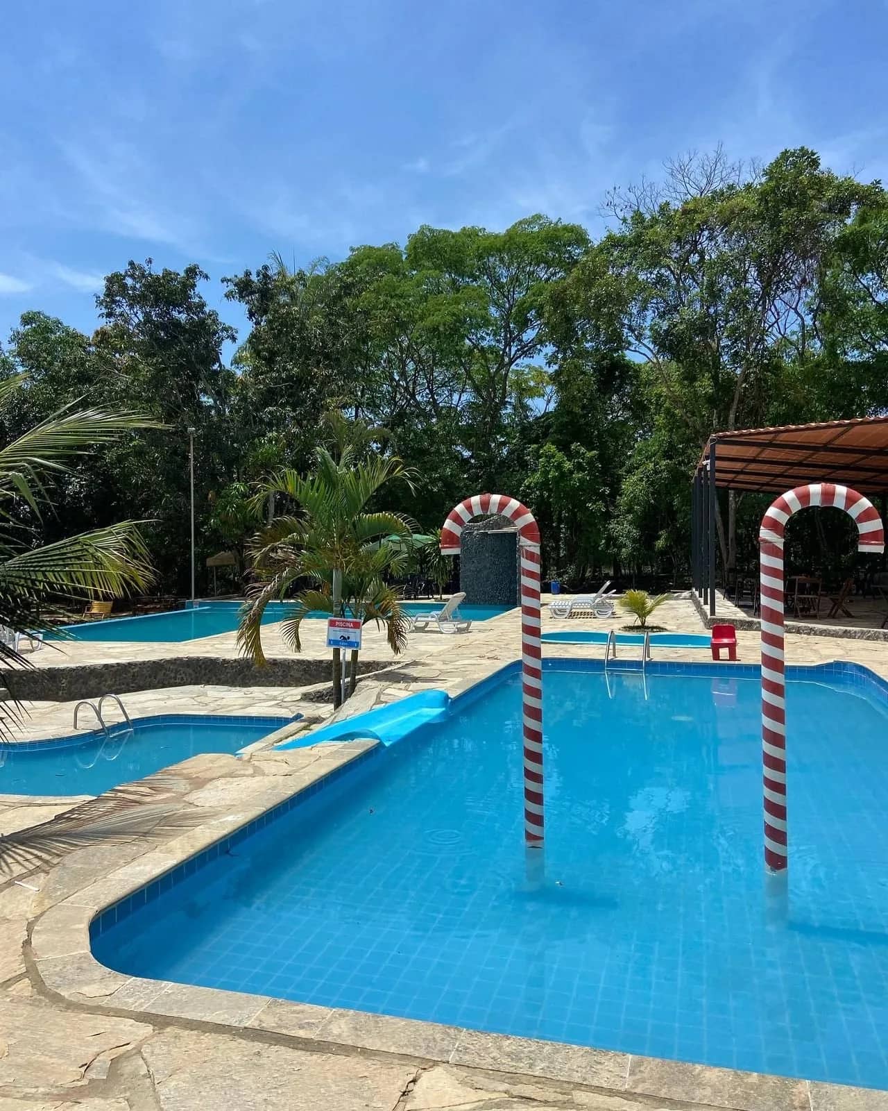 Conjunto de piscinas azuis com escorregador e chuveiros em formato de bengala