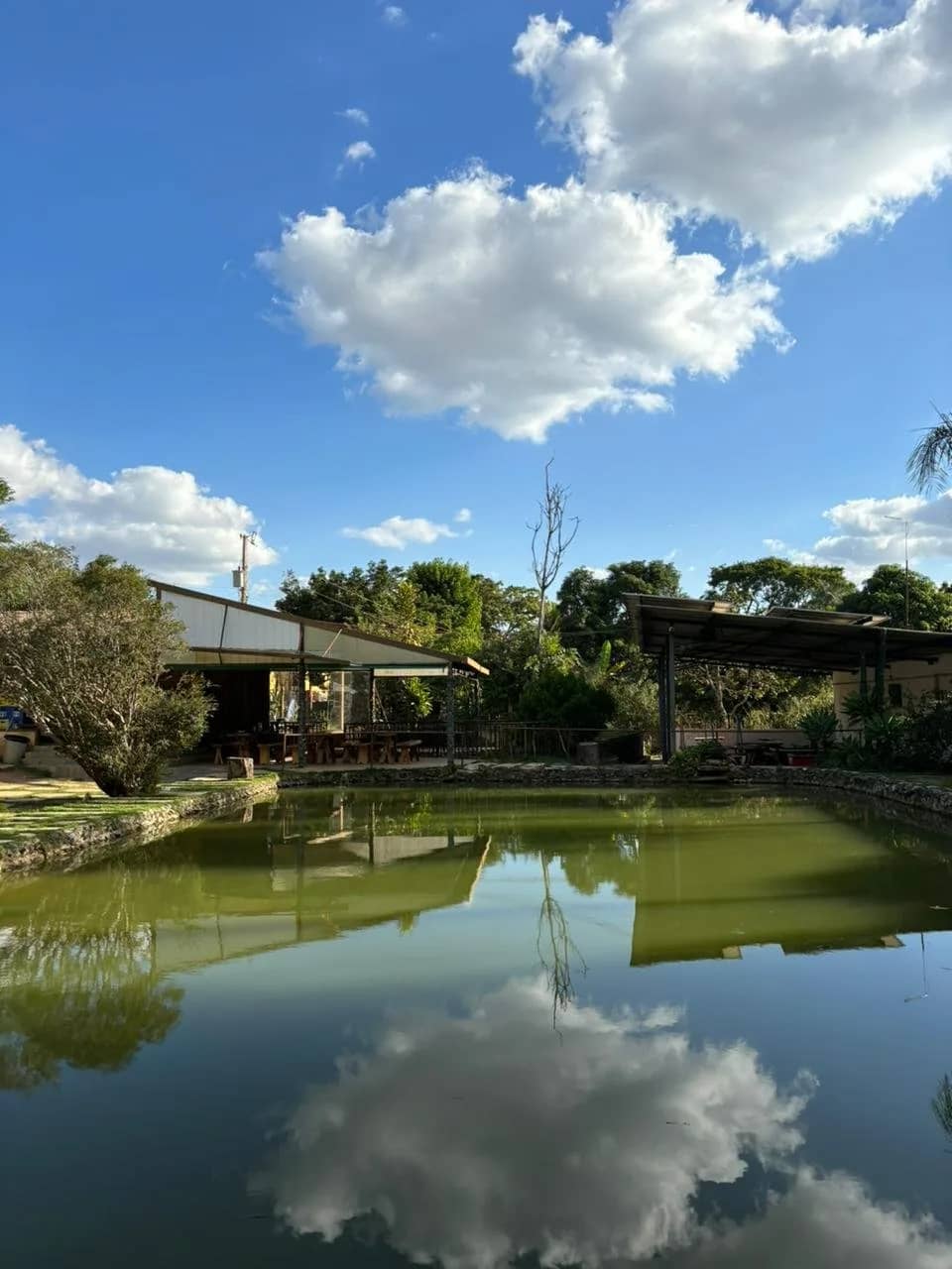 Lagoa espelhando nuvens com o salão de refeições coberto ao fundo