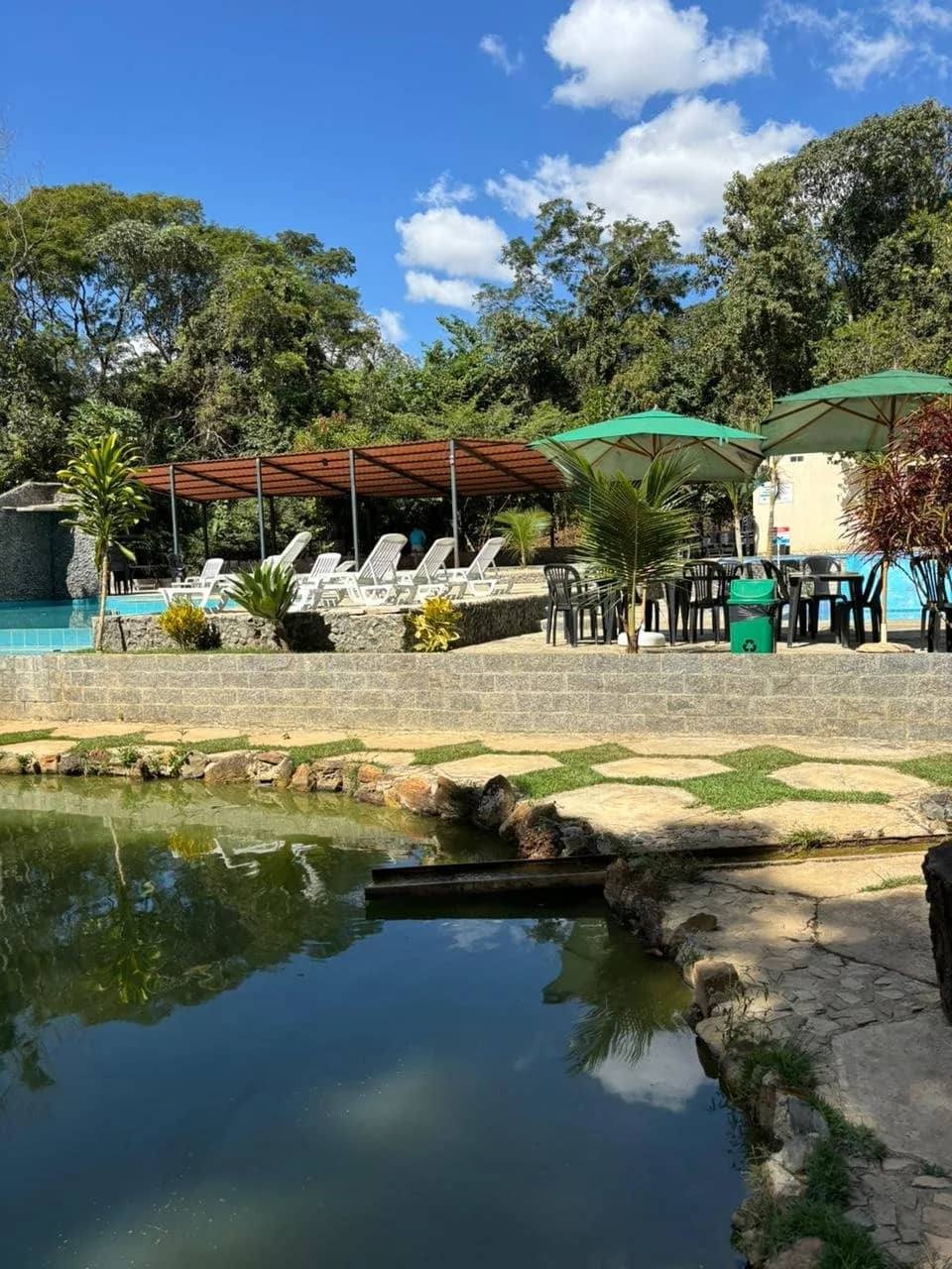 Espreguiçadeiras e guarda-sóis na área da piscina vistos do outro lado da lagoa
