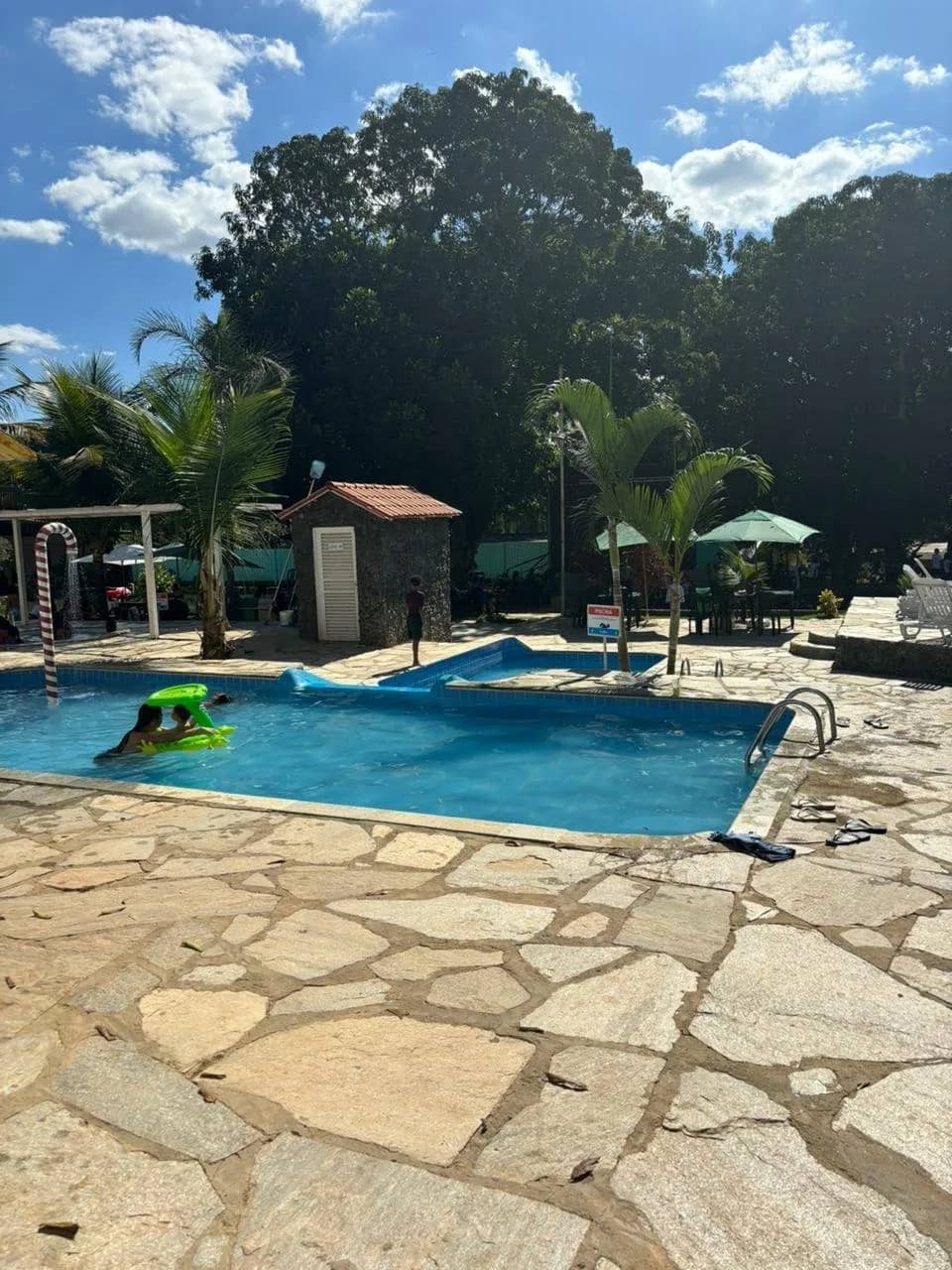 Crianças brincando com boia inflável na piscina em dia ensolarado