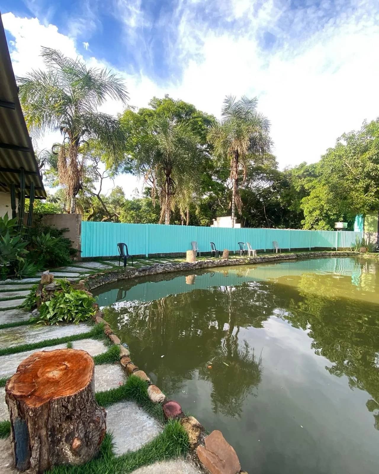Lagoa com cadeiras enfileiradas na margem e palmeiras refletidas na água