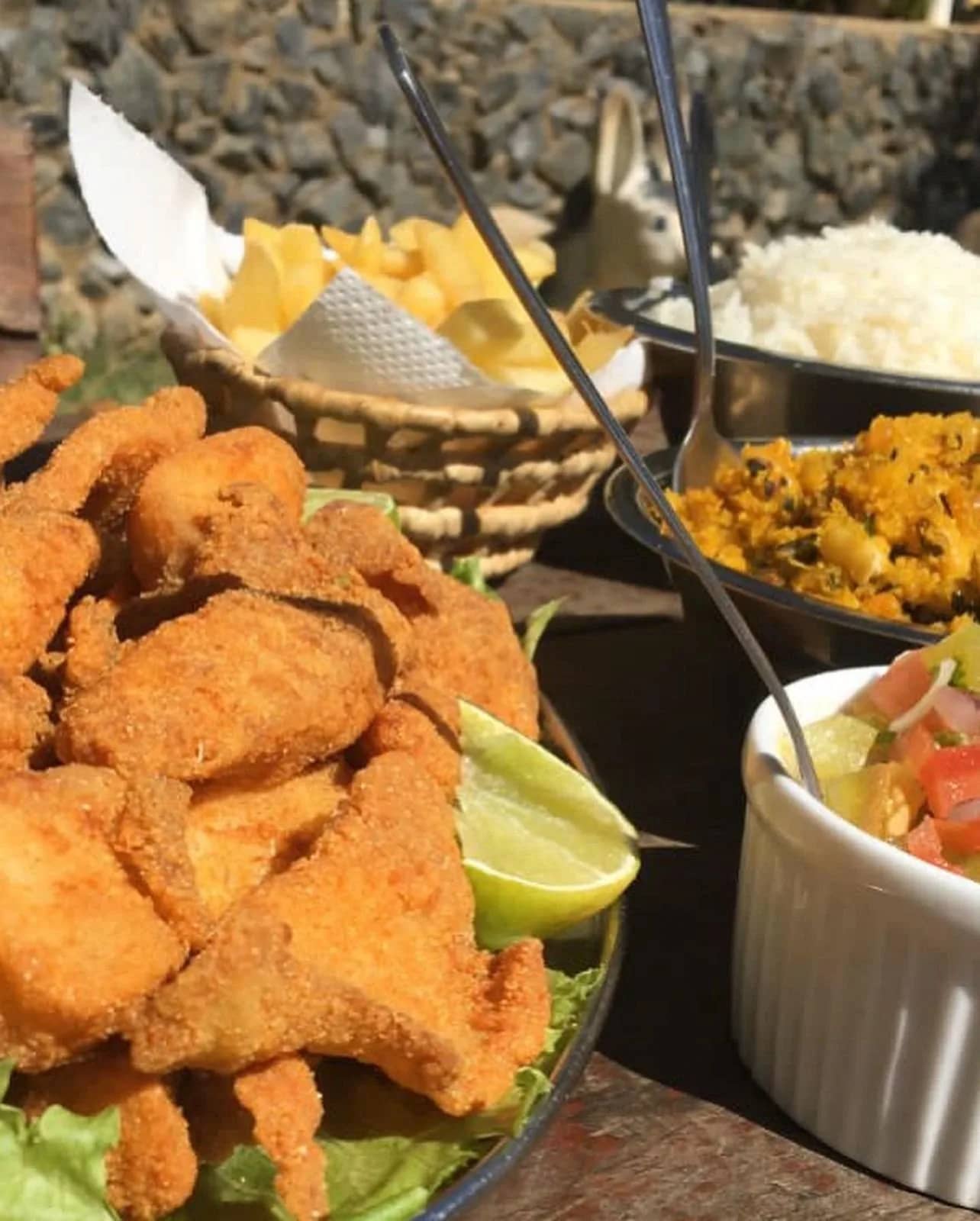Iscas de peixe empanadas com limão, batata chips, arroz, farofa e vinagrete