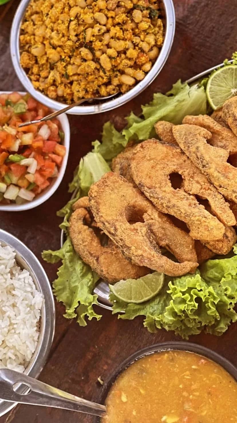 Postas de peixe frito sobre alface com feijão tropeiro, arroz e vinagrete